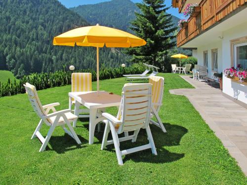 een tafel en stoelen met een parasol op een gazon bij Apartment Ornella-1 by Interhome in Santa Cristina in Val Gardena