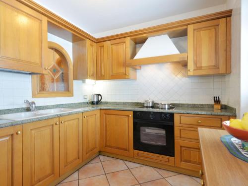 a kitchen with wooden cabinets and a black stove top oven at Apartment Ardoney-1 by Interhome in Campitello