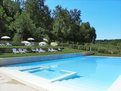 a swimming pool with chairs and umbrellas in a yard at Apartment Francigena-4 by Interhome in Castelnuovo D'elsa