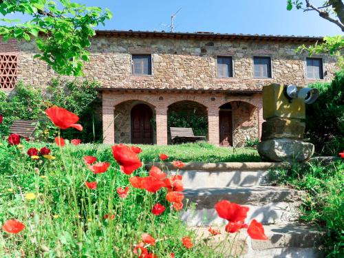 a stone building with red flowers in front of it at Holiday Home Agrumi by Interhome in Montevettolini