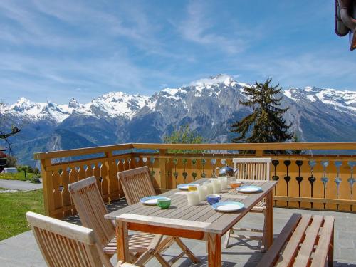 un tavolo in legno con sedie e un balcone con vista sulle montagne. di Chalet Ratatouille by Interhome a Nendaz