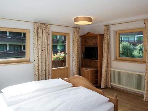 a bedroom with a bed and two windows at Holiday Home Sonnheim by Interhome in Auffach