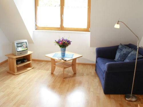 a living room with a blue couch and a table with flowers at Apartment Dieboldshof by Interhome in Neuried