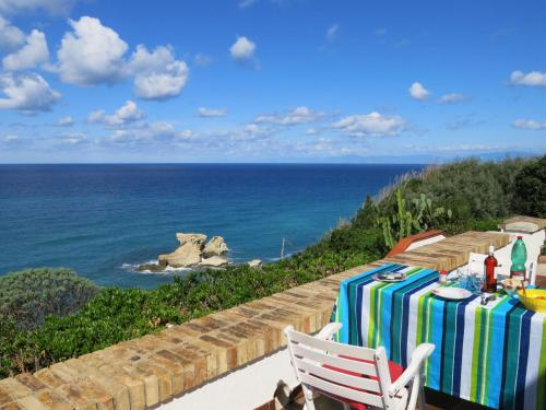 a table and a white chair and the ocean at Apartment Sulla Scogliera by Interhome in Santa Domenica