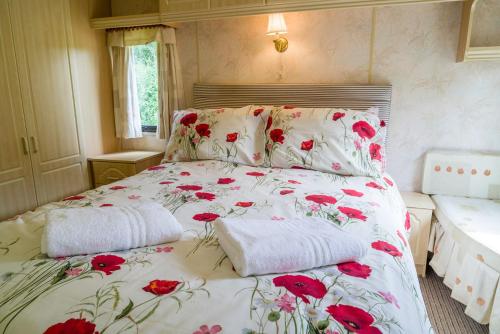 Una cama con flores rojas y dos almohadas en Tadpole Retreat at Lower Fields Farm, en Napton on the Hill