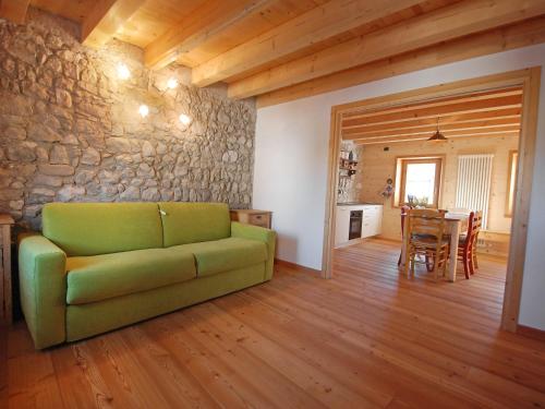 - un salon avec un canapé vert et un mur en pierre dans l'établissement Apartment Albergo Diffuso - Cjasa Ustin-1 by Interhome, à Barcis