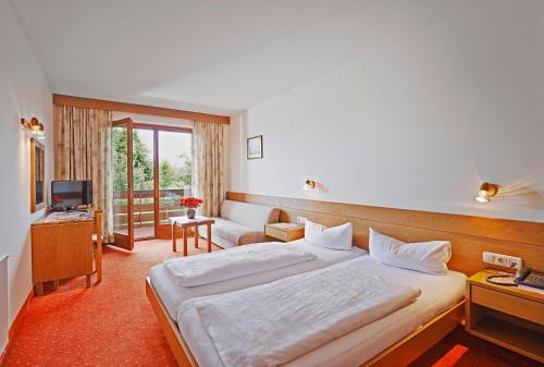 una camera d'albergo con un grande letto e una TV di Finkensteiner Hof a Finkenstein am Faaker See