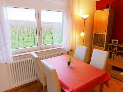 uma sala de jantar com uma mesa vermelha e 2 janelas em Apartment Haus Sacherer by Interhome em Bischoffingen
