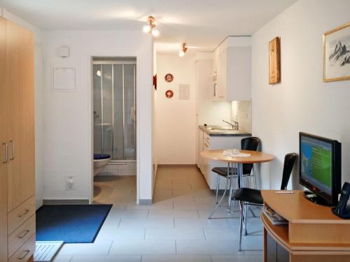 eine Küche und ein Wohnzimmer mit einem Tisch und einem TV in der Unterkunft Apartment Chalet am Reeti by Interhome in Grindelwald