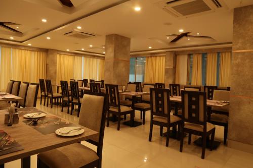 a restaurant with tables and chairs in a room at Hotel Girija Sunrise in Deoghar