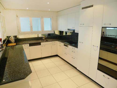 eine Küche mit weißen Schränken und schwarzen Arbeitsplatten in der Unterkunft Apartment Hegglistrasse 9-1 by Interhome in Buochs