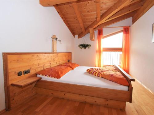 Schlafzimmer mit einem Bett mit einem Kopfteil aus Holz und einem Fenster in der Unterkunft Apartment Hansjörg-4 by Interhome in Gattererberg