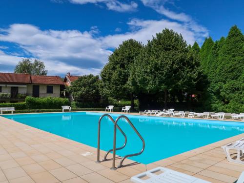 a large swimming pool with chairs and trees at Apartment Blue Lagoon by Interhome in  Monvalle 