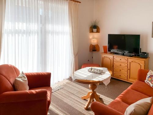 a living room with a tv and a couch and a table at Apartment Dehne-1 by Interhome in Norddeich