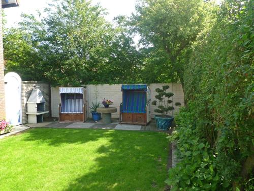 a backyard with a yard with green grass and trees at Apartment Dehne-1 by Interhome in Norddeich