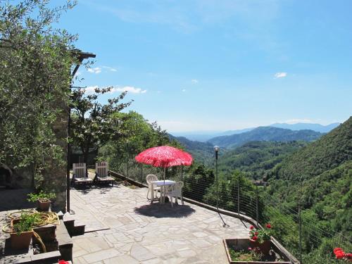 eine Terrasse mit einem Tisch und einem roten Regenschirm in der Unterkunft Holiday Home Castagneto by Interhome in Loppeglia