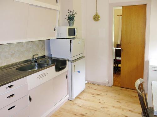 a white kitchen with a sink and a microwave at Holiday Home Olavbu - SOW105 by Interhome in Åseral
