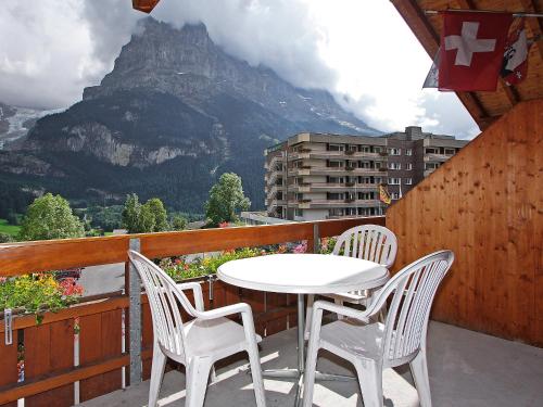 a white table and chairs on a balcony with a mountain at Apartment Chalet Abendrot-23 by Interhome in Grindelwald