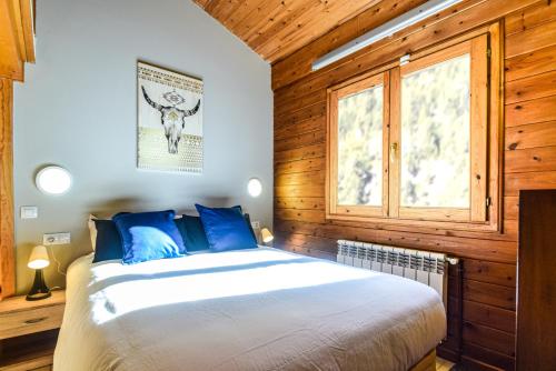 ein Schlafzimmer mit einem Bett mit blauen Kissen und einem Fenster in der Unterkunft Preciosa Pleta en la Vall d’Incles HUT 7960 in Canillo