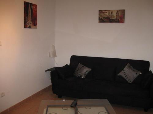 un salon avec un canapé noir et une table dans l'établissement GITE DES FRANCISCAINS-Imiza, à Canari