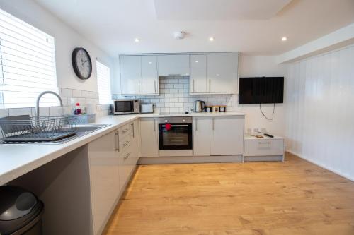 a kitchen with white cabinets and a clock on the wall at Stylish Studio in the Heart of the English Riviera in Torquay