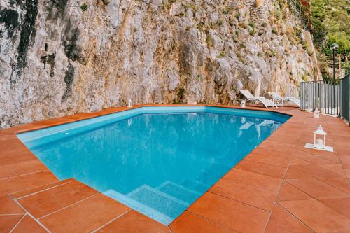 a swimming pool in front of a rock wall at Villa Eris Amalfi Coast in Conca dei Marini