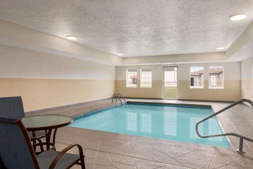 a swimming pool with a table and a chair at Microtel Inn & Suites Lincoln in Lincoln