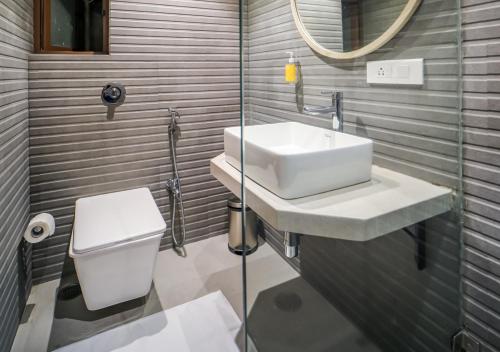 een badkamer met een wastafel, een toilet en een spiegel bij Bloom Hotel - Juhu in Mumbai