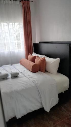 1 cama blanca grande con 2 almohadas y ventana en Bloom private home en Thika