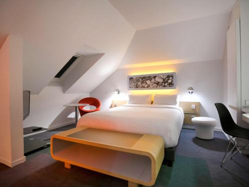 a hotel room with a bed and a table and chairs at Mercure Nantes Centre Gare in Nantes