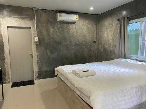 a bedroom with a white bed and a wall at บ้านสวนวงศ์จินดารักษ์ in Phayao