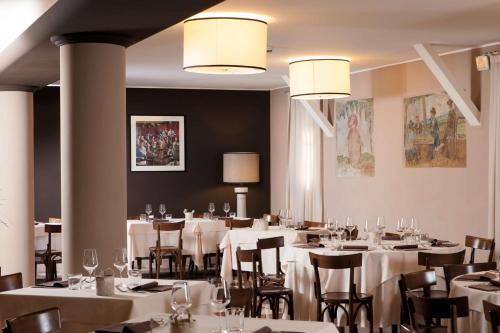 un comedor con mesas blancas, sillas y luces en BEST WESTERN Titian Inn Hotel Treviso, en Silea