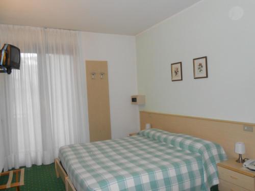 a bedroom with a bed with a checkered blanket at Albergo Genzianella in Fiavè