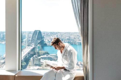 a man sitting on a balcony looking at the ocean at Shangri-La Sydney in Sydney