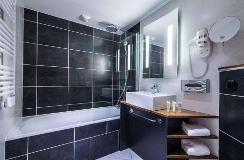 a bathroom with a sink and a tub and a mirror at Best Western Plus Suitcase Paris La Défense in Bois-Colombes