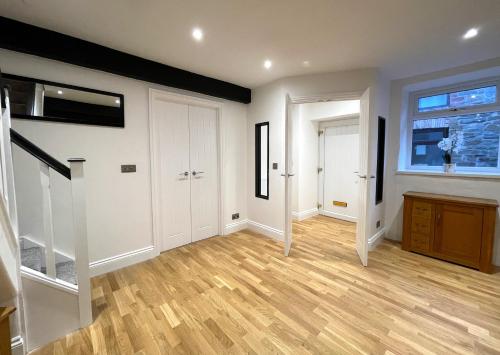 an empty living room with a staircase and a window at Yr Hen Bopty (The Old Bakery) in Pontypridd