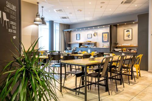 ボワ・コロンブにあるベストウェスタン プラス スーツケース パリ ラデファンスのテーブルと椅子のあるレストラン、カフェテリア