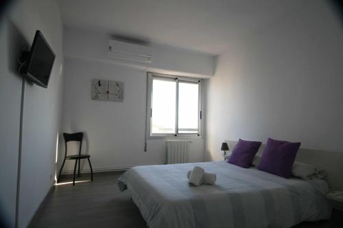 ein Schlafzimmer mit einem Bett mit lila Kissen und einem Fenster in der Unterkunft Las Minvas Teatro in Castellón de la Plana