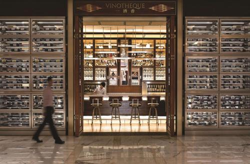 a woman walks past a wine display in a store at Kerry Hotel, Beijing by Shangri-La - 5 Kilometers to The Forbidden City in Beijing