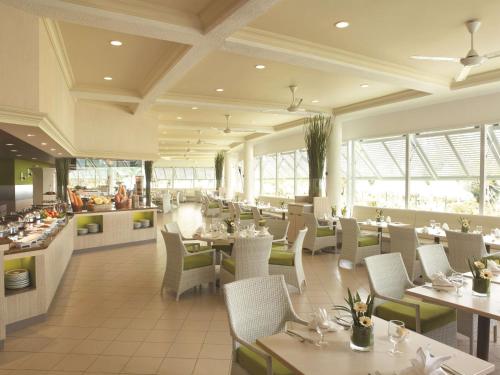 a restaurant with white tables and chairs and windows at Shangri-La Golden Sands, Penang in Batu Ferringhi