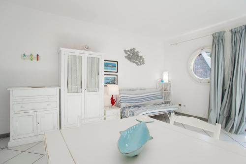 um quarto branco com uma cama e uma secretária em Monolocale Il Porto 3 em Porto Azzurro