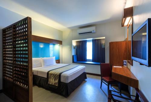 a hotel room with a bed and a television at Microtel by Wyndham UP Technohub in Manila