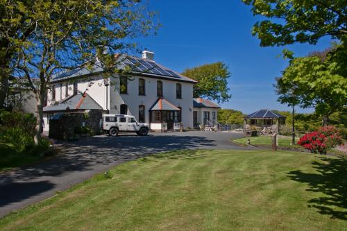 una casa bianca con un camion bianco parcheggiato nel vialetto. di Pendragon Country House a Camelford