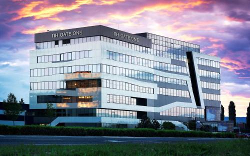 a large office building with a sunset in the background at NH Bratislava Gate One in Bratislava