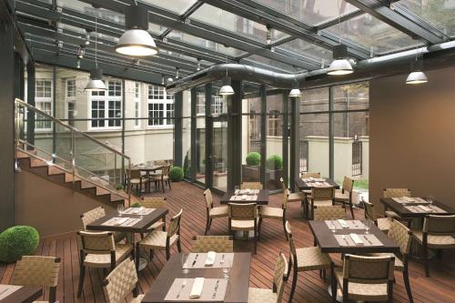 restauracja ze stołami, krzesłami i oknami w obiekcie Hotel NH Poznan w Poznaniu