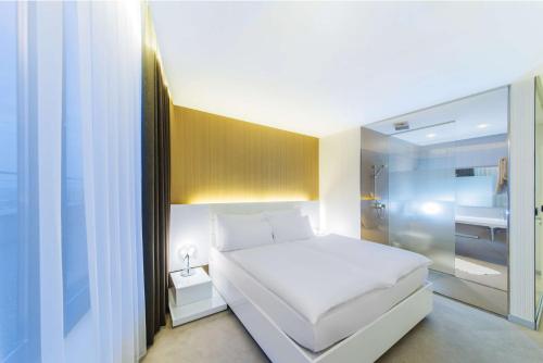 a small bedroom with a white bed and a shower at NH Bratislava Gate One in Bratislava
