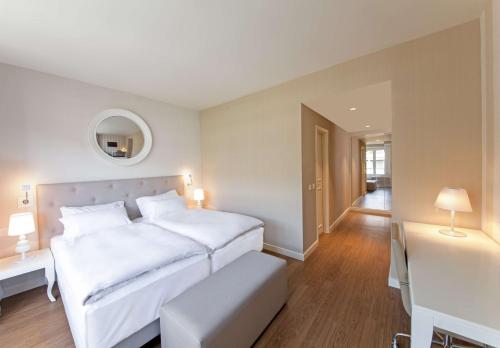 a white bedroom with a large bed and a table at Geneva by Fassbind in Geneva