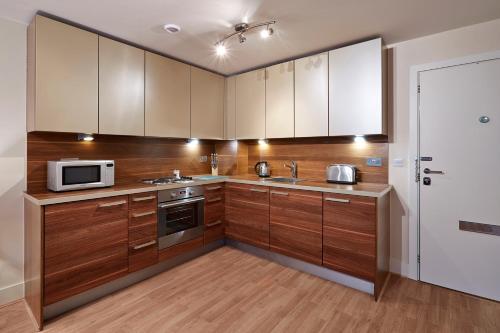 a kitchen with wooden cabinets and a microwave at Skyline Plaza By Viridian Apartments in Basingstoke