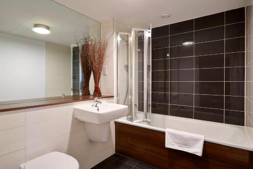 a bathroom with a sink and a toilet and a tub at Skyline Plaza By Viridian Apartments in Basingstoke