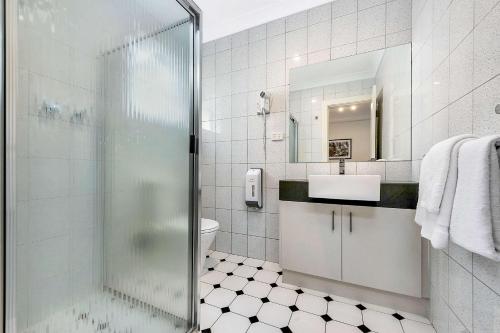 Adelaide的住宿－曼哈頓康福特酒店，一间带玻璃淋浴和水槽的浴室